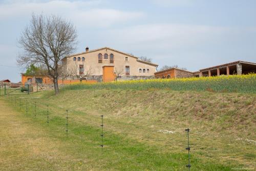 a house on top of a grassy hill with poles at Mas Teixidor, Masia entre Girona y la Costa Brava in Caldes de Malavella