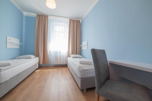 a room with two beds and a chair and a window at Freedom Hostel in Kraków