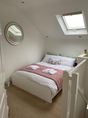 a white bedroom with a bed with a mirror at Orchard cottage in Pucklechurch