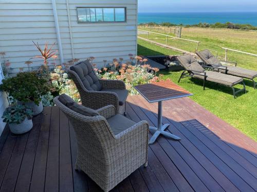 a deck with two chairs and a table and a table at Seacroft Estate in Apollo Bay