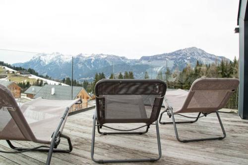two chairs sitting on a deck with mountains in the background at Exclusive Alpenlodge ski in ski out Galsterberg in Pruggern