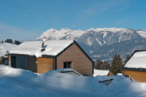 a building covered in snow with mountains in the background at Exclusive Alpenlodge ski in ski out Galsterberg in Pruggern