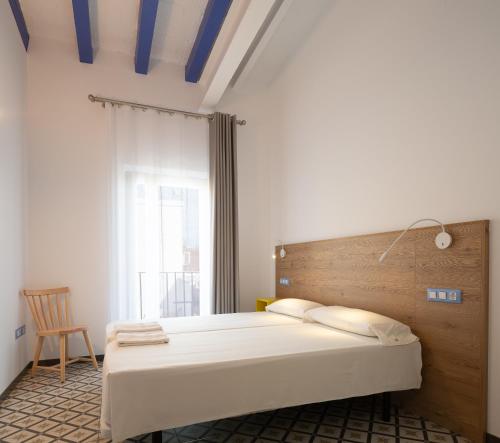 Schlafzimmer mit einem Bett mit einem Kopfteil aus Holz und einem Stuhl in der Unterkunft Tgna Cervantes 8 in Tarragona