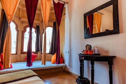 a bedroom with a window with red curtains and a mirror at Hotel Lal Garh Fort And Palace in Jaisalmer