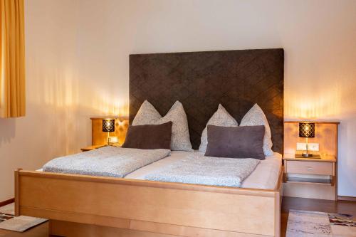 a bedroom with a large bed with a wooden headboard at Appartementhaus Bergland in Obsteig