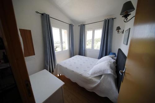 1 dormitorio pequeño con 1 cama y 2 ventanas en Les Oliviers, en Grimaud