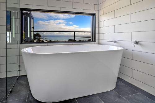 a white bath tub in a bathroom with a window at Atelier in Coles Bay