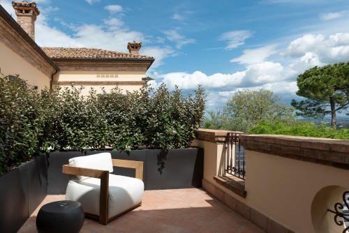 a balcony with a white chair and a building at Relais Villa Margherita in Longiano
