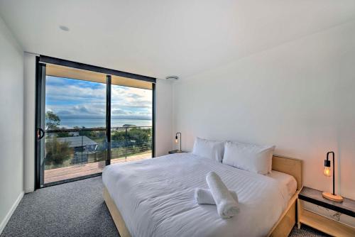 a bedroom with a white bed with a large window at Atelier in Coles Bay