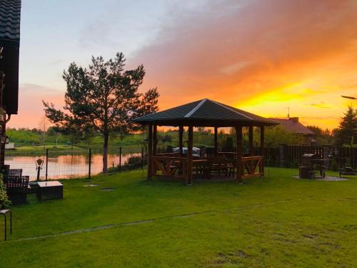 a gazebo with a picnic table and a lake at Villa Lotus in Zhemoytele