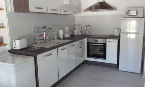 eine weiße Küche mit einer Spüle und einem Kühlschrank in der Unterkunft Gîte de La Garenne in Cozes