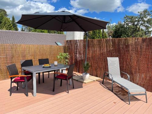 a table and chairs with an umbrella on a deck at Ferienwohnung Kaiserblick in Stephanskirchen