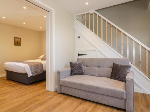 a bedroom with a bed and a couch and a staircase at The Granary in Bodmin