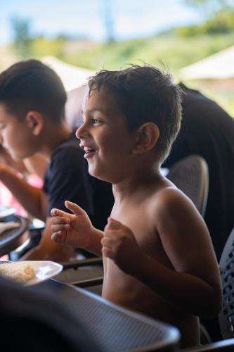 a young boy smiles while sitting at a table at Kokalas Resort in Georgioupolis