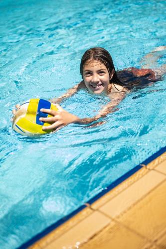 a young girl in a swimming pool with a ball at Kokalas Resort in Georgioupolis