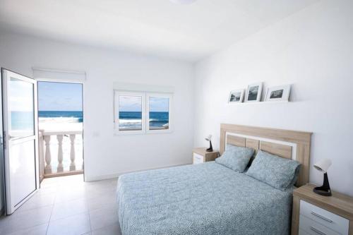sypialnia z łóżkiem i widokiem na ocean w obiekcie Horizonte Atlántico: Un Rincón en el Paraíso w mieście Azano