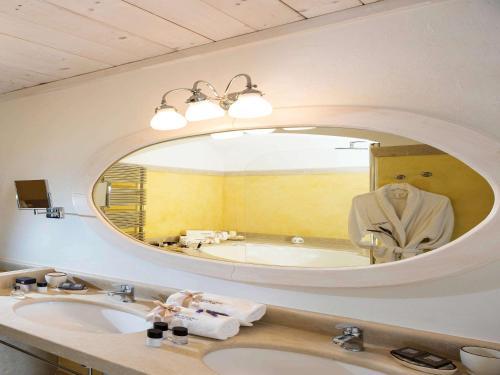 a bathroom with a sink and a large mirror at Borgobianco Resort & Spa Polignano - MGallery Collection in Polignano a Mare