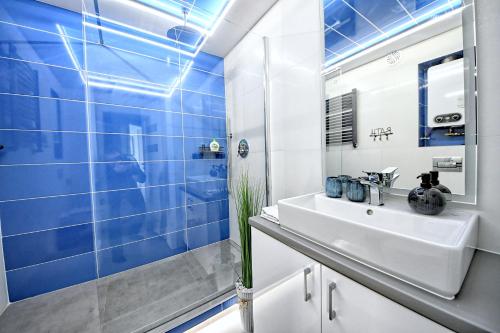 baño con lavabo blanco y azulejos azules en Belweder, en Nałęczów