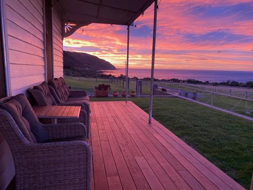 a wooden deck with couches on a house with a sunset at Seacroft Estate in Apollo Bay