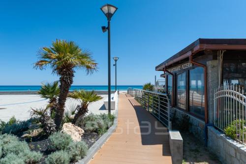 a boardwalk along the beach with a palm tree at Villa Katia in Simius