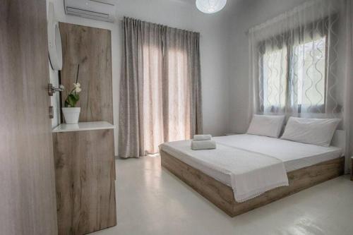 a white bedroom with a bed and a window at Athina's home 2 in Ayios Nikolaos Sithonia