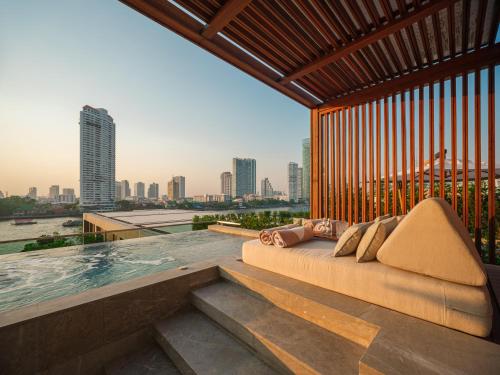 un letto posto in cima a un edificio con piscina di Capella Bangkok a Bangkok