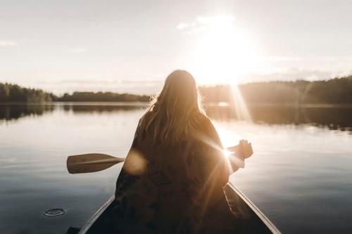a woman is sitting in a canoe on a lake at Villa Myttinge in Värmdö