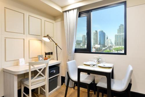 a dining room with a table and chairs and a window at Oakwood Hotel & Residence Bangkok in Bangkok