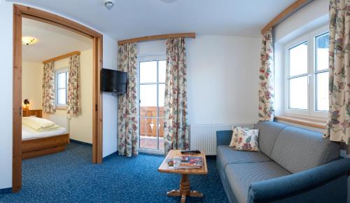 a room with a couch and a bed and a window at Naturhotel Hüttenwirt im Grossarltal in Hüttschlag