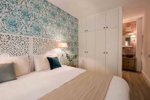 una camera da letto con un letto bianco e carta da parati blu e bianca di HOMEABOUT GOYA Apartment II a Madrid