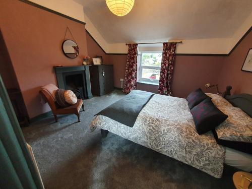 a bedroom with a bed and a chair and a fireplace at Cosy Cottage in heart of Llangollen in Llangollen