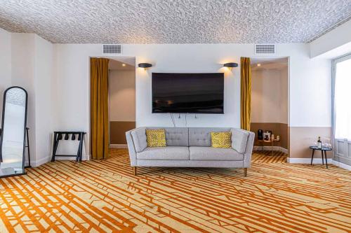 a living room with a couch and a flat screen tv at Hotel Le Saint Gelais in Angoulême