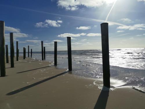a row of poles in the water on a beach at Duinberk B&B hotel en Brasserie in Schoorl