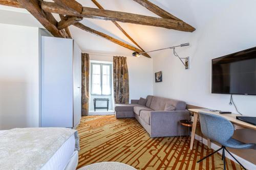 a room with a bed and a couch and a tv at Hotel Le Saint Gelais in Angoulême