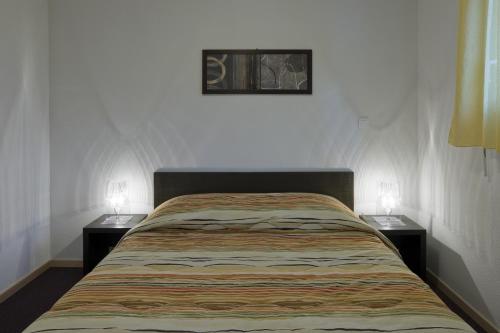 a bed in a room with two nightstands and two lamps at Noemys Terrasses de Labrau in La Foux