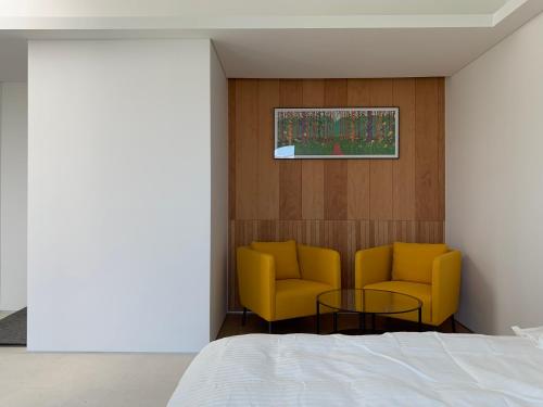 a bedroom with two yellow chairs and a table at Laon on 37 in Tongyeong