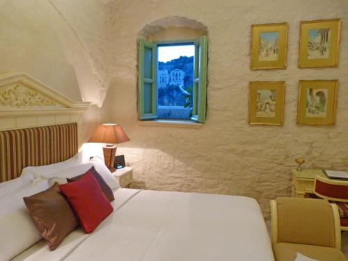 a bedroom with a white bed and a window at The Old Markets in Symi