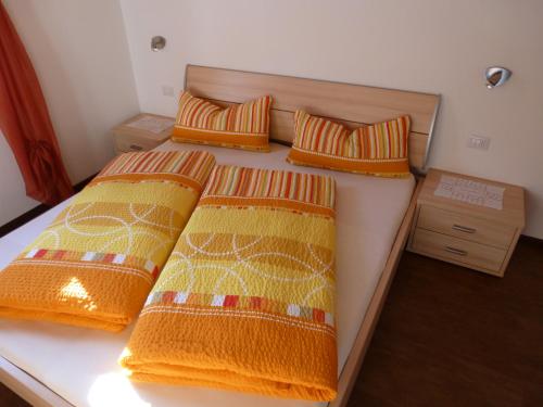 1 Schlafzimmer mit 2 Betten mit orangefarbenen und gelben Decken in der Unterkunft Polzhof in Kastelruth