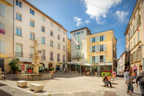 a group of people walking around a street with buildings at Provence Au Coeur Appart Hotels in Forcalquier