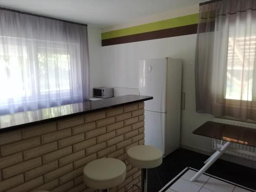 - une cuisine avec un réfrigérateur blanc et deux tabourets dans l'établissement Maci Vendégház, à Békéscsaba
