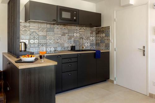 a kitchen with a sink and a counter with a bowl of oranges at Provence Au Coeur Appart Hotels in Forcalquier