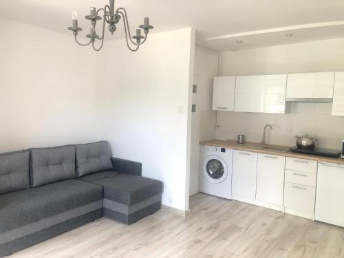 a living room with a couch and a kitchen at Apartament Wygodny S5 in Kalisz