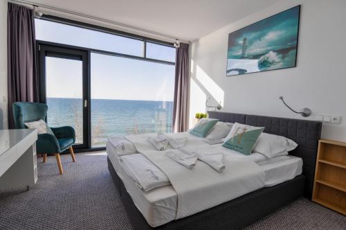 Un dormitorio con una cama grande con vista al mar. en Apartament Nadmorski Luksus - Boulevard, en Ustronie Morskie