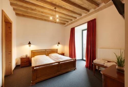 カンポ・ディ・トレンスにあるHistoric Guesthouse BIRCHER B&B Apartments near Sterzingのベッドと赤いカーテンの窓がある寝室