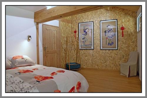 a bedroom with a bed and some pictures on the wall at LES CHAMBRES DE LIANE in Cerdon