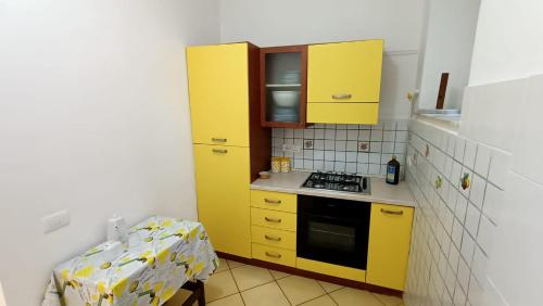 une petite cuisine avec des armoires jaunes et une table dans l'établissement Casa vacanze da Cristina app B, à Maratea