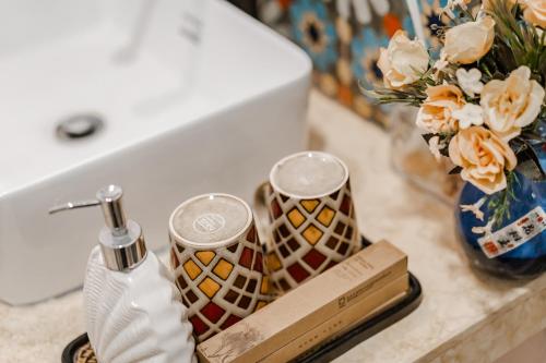 a bathroom counter with a sink with a bottle of soap and flowers at Baisha Flamingo Hotel in Lijiang