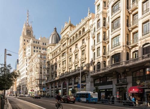ruchliwa ulica miejska z wysokimi budynkami i osoba jeżdżąca na rowerze w obiekcie My Citymad Stay Madrid w Madrycie