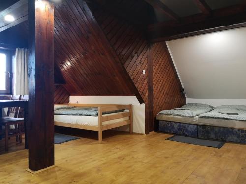 two beds in a room with wooden walls at Motorest SKI Čertovica in Vyšná Boca