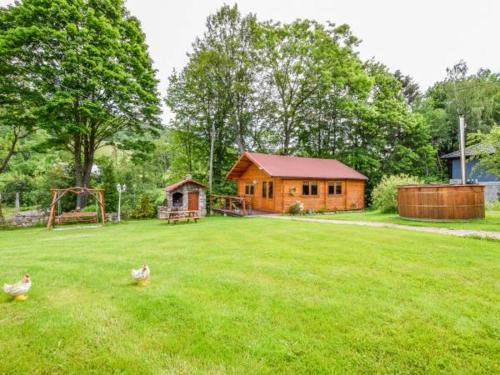 una cabaña de madera en un patio con dos patos en la hierba en Pokoje Gościnne Poniatowscy, en Świeradów-Zdrój